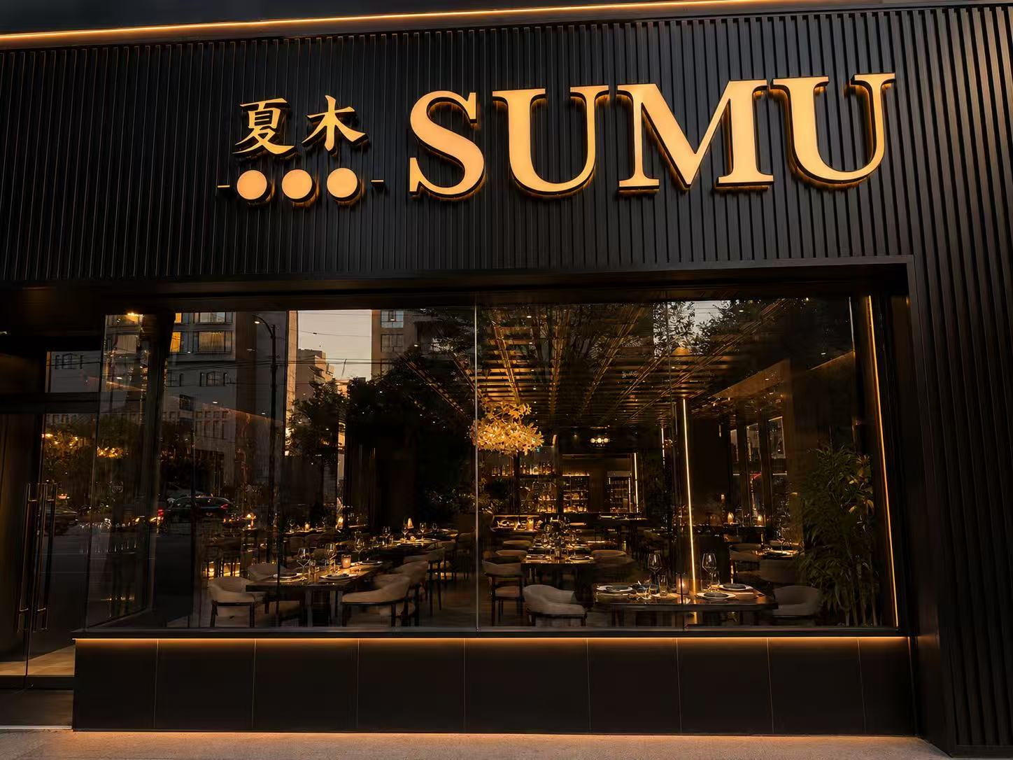 The SUMU storefront at dusk, gold illuminated signage above the dining room windows