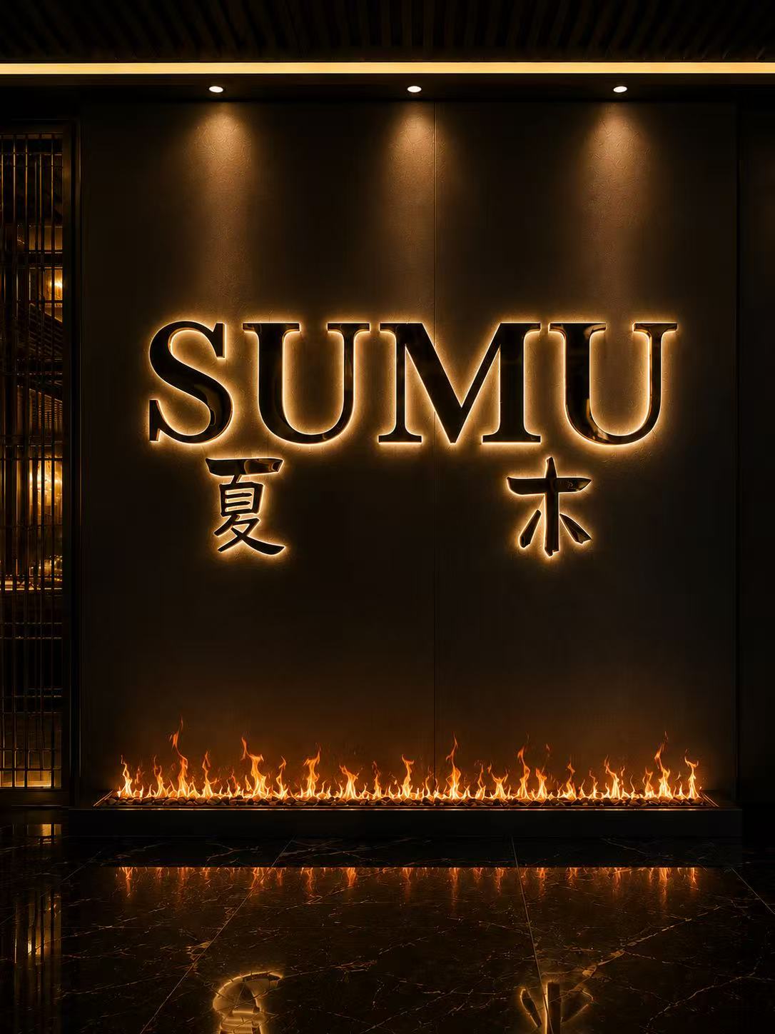 The illuminated SUMU signage above the fire feature at the entrance